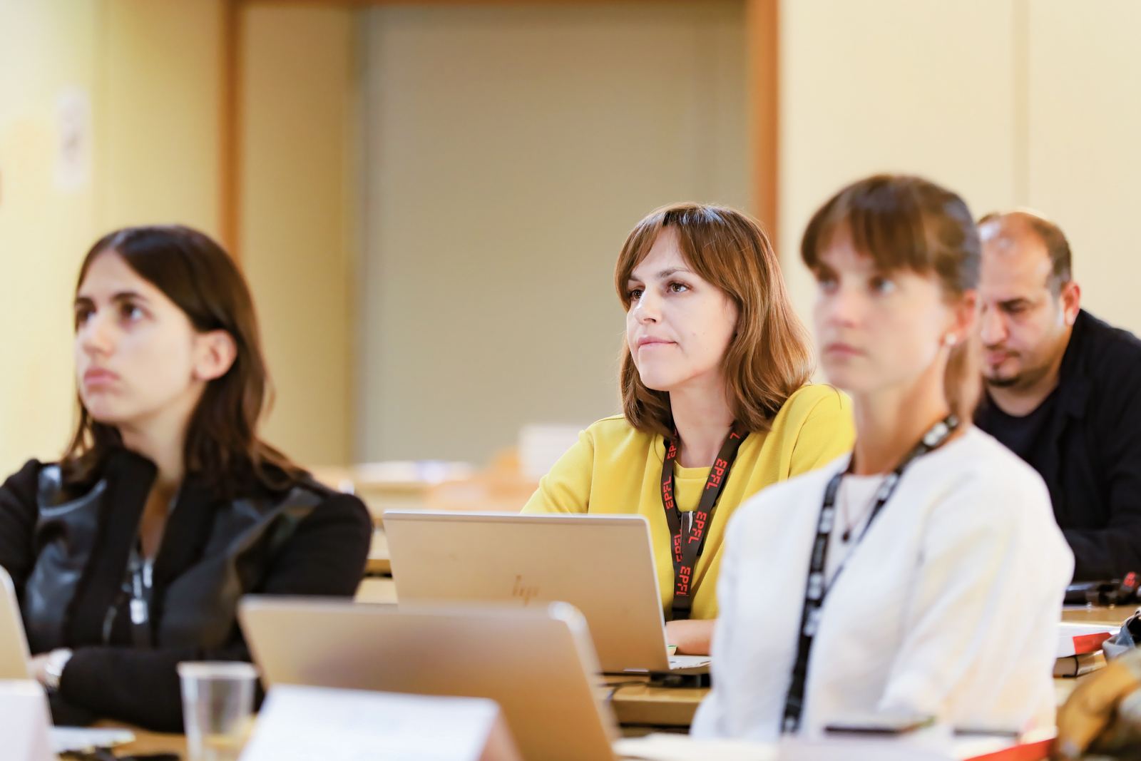 Executive-program participants follow a lecture, laptops open, wearing EPFL lanyards